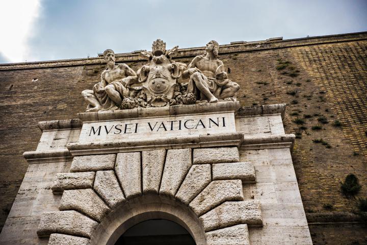 a stone building that has a clock at the top of a brick wall