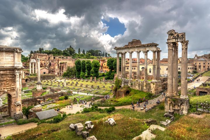 a castle on top of a grass covered field with Roman Forum in the background
