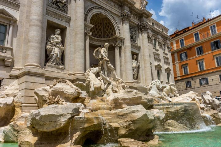 a large stone statue in front of Trevi Fountain
