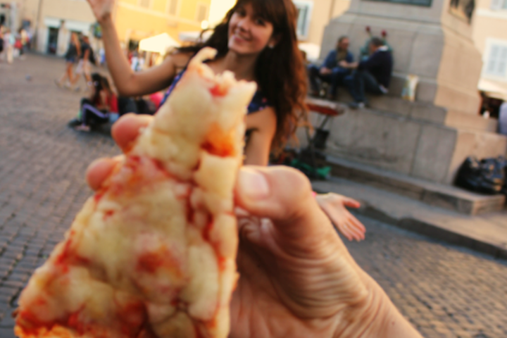 a person holding a piece of pizza
